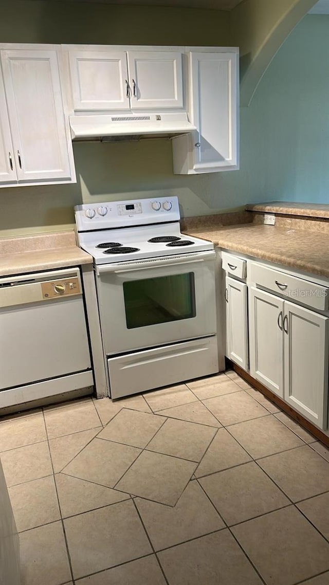 kitchen featuring white appliances, light tile patterned flooring, and white cabinets