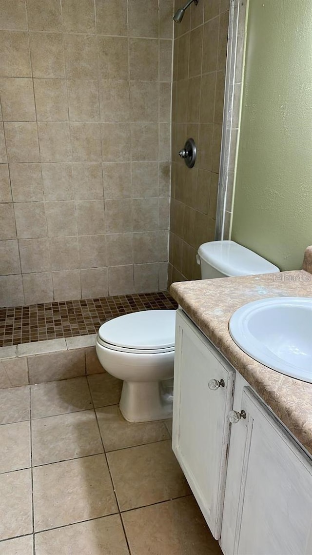 bathroom with a tile shower, tile patterned floors, vanity, and toilet