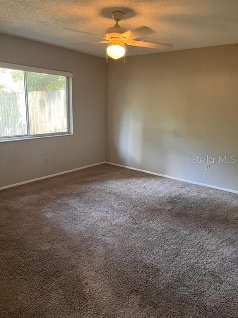 carpeted spare room featuring ceiling fan and a textured ceiling