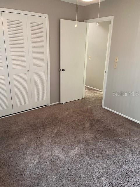 unfurnished bedroom featuring dark carpet and a closet