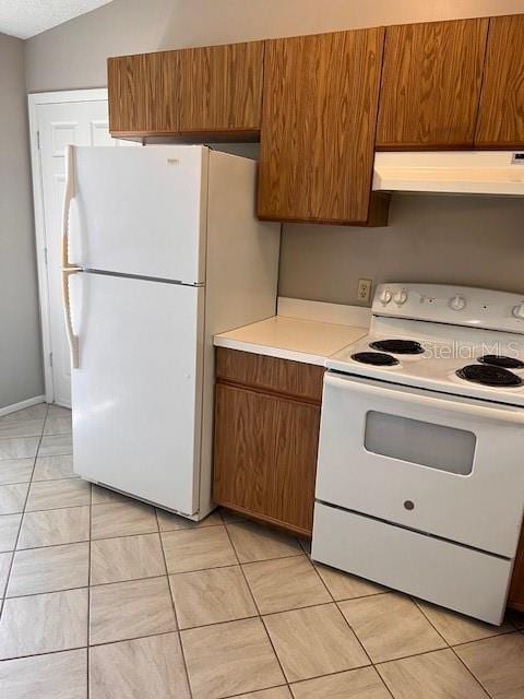 kitchen featuring lofted ceiling, white appliances, and light tile patterned floors