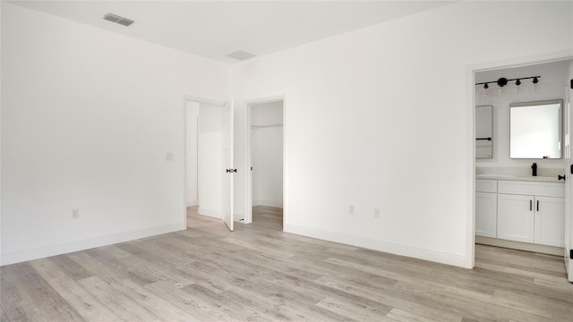 unfurnished bedroom featuring light hardwood / wood-style flooring and connected bathroom