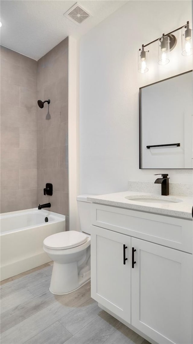 full bathroom with tiled shower / bath combo, vanity, and toilet