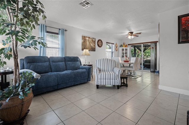 tiled living room featuring ceiling fan and a textured ceiling