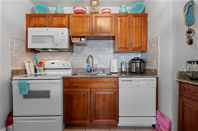 kitchen featuring dark stone countertops, sink, white appliances, and backsplash