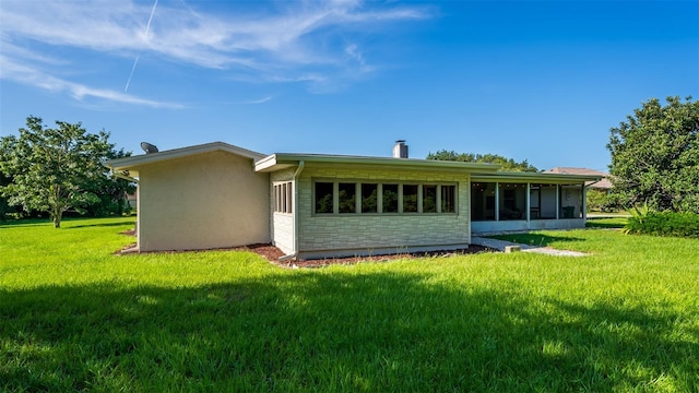 rear view of house with a lawn and a sunroom