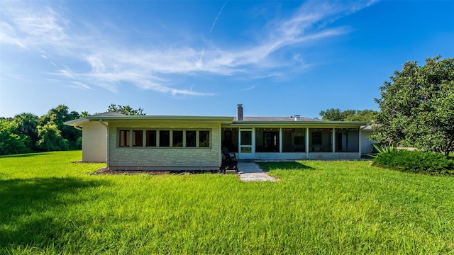 rear view of house featuring a lawn and a sunroom