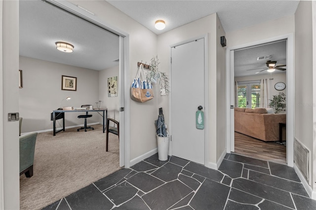 carpeted foyer entrance with ceiling fan and a textured ceiling