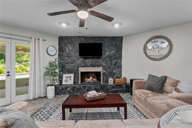 living room featuring wood-type flooring, a textured ceiling, a fireplace, and ceiling fan