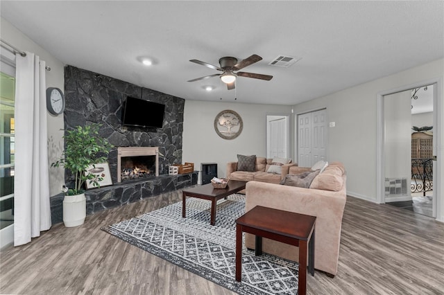 living room with a textured ceiling, a fireplace, hardwood / wood-style floors, and ceiling fan