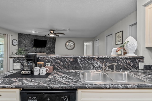 kitchen with ceiling fan, sink, white cabinetry, dishwasher, and a fireplace