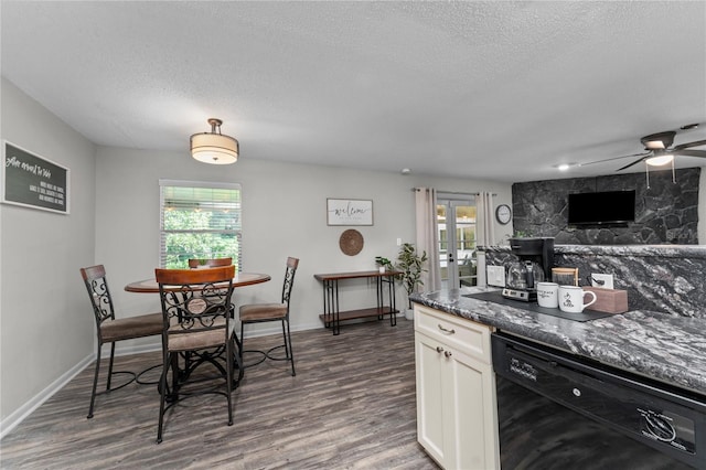 kitchen featuring dark stone countertops, dark wood-type flooring, white cabinets, black dishwasher, and ceiling fan