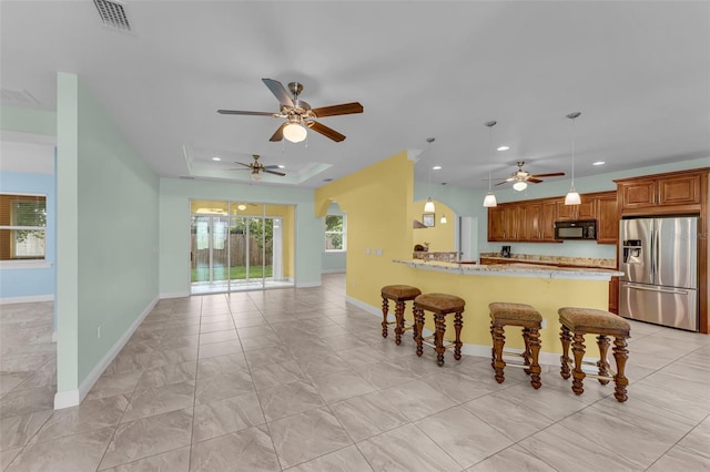 kitchen with kitchen peninsula, stainless steel refrigerator with ice dispenser, a breakfast bar, and a wealth of natural light