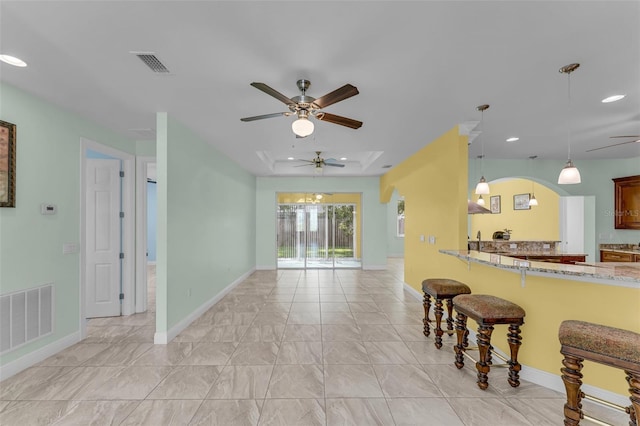 kitchen featuring kitchen peninsula, a kitchen breakfast bar, decorative light fixtures, and ceiling fan