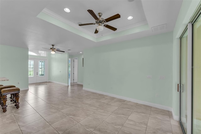 empty room featuring ceiling fan, a raised ceiling, and french doors