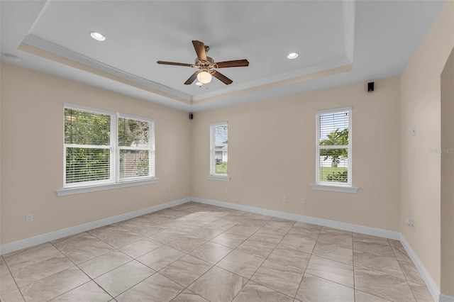 empty room with ceiling fan, a raised ceiling, and ornamental molding