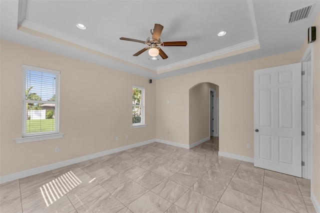 spare room featuring a raised ceiling, a wealth of natural light, ceiling fan, and ornamental molding