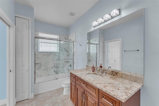 full bathroom featuring vanity, toilet, and shower / bath combination with glass door