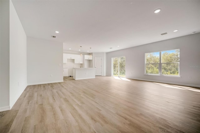 unfurnished living room with light hardwood / wood-style floors and sink