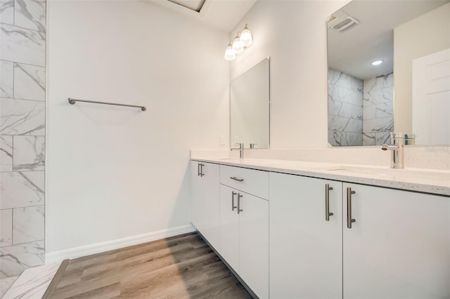 bathroom with a tile shower, vanity, and hardwood / wood-style floors