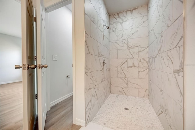 bathroom with a tile shower and hardwood / wood-style floors