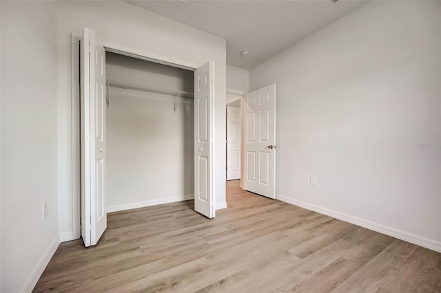 unfurnished bedroom with light wood-type flooring and a closet