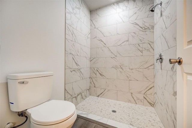 bathroom with a tile shower and toilet