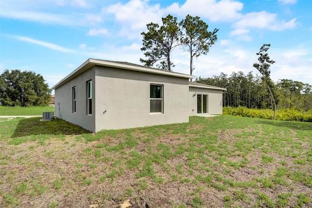 back of property featuring cooling unit and a yard