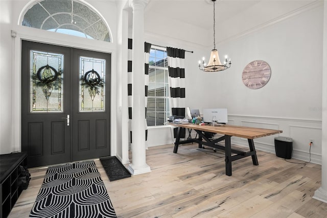 entryway featuring an inviting chandelier, light wood-type flooring, decorative columns, and a wealth of natural light