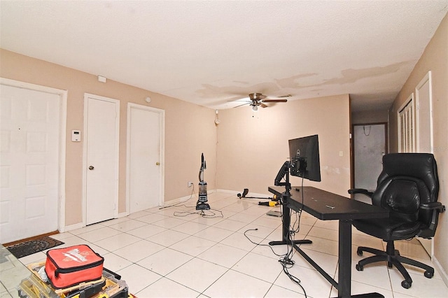 exercise room featuring a textured ceiling, light tile patterned flooring, and ceiling fan