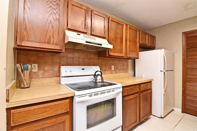 kitchen with light tile patterned floors, white appliances, and decorative backsplash