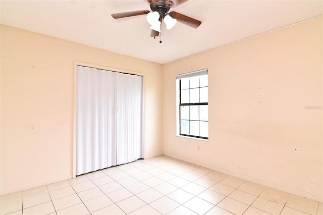 tiled spare room with ceiling fan and a textured ceiling