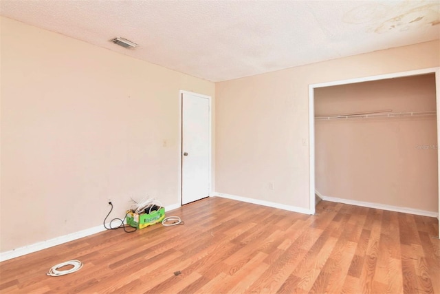 unfurnished bedroom featuring a textured ceiling, light hardwood / wood-style flooring, and a closet