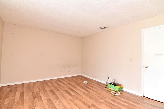 empty room featuring a textured ceiling and light hardwood / wood-style flooring