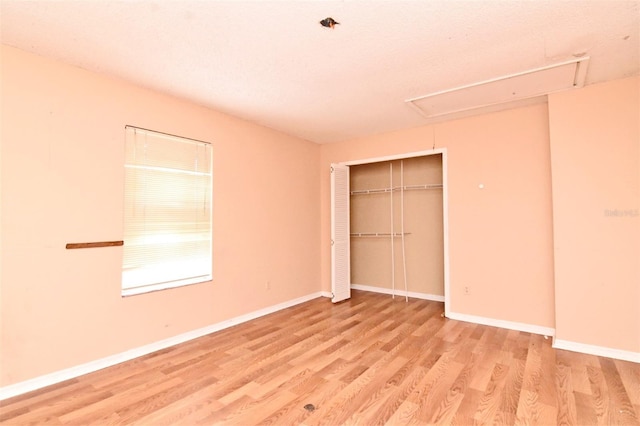 unfurnished bedroom featuring a textured ceiling, wood-type flooring, and a closet