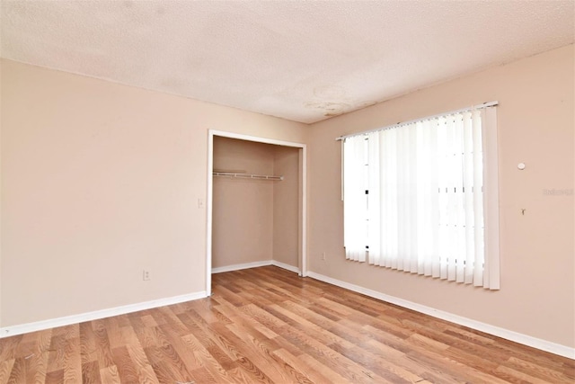 unfurnished bedroom with light hardwood / wood-style flooring, a closet, and a textured ceiling