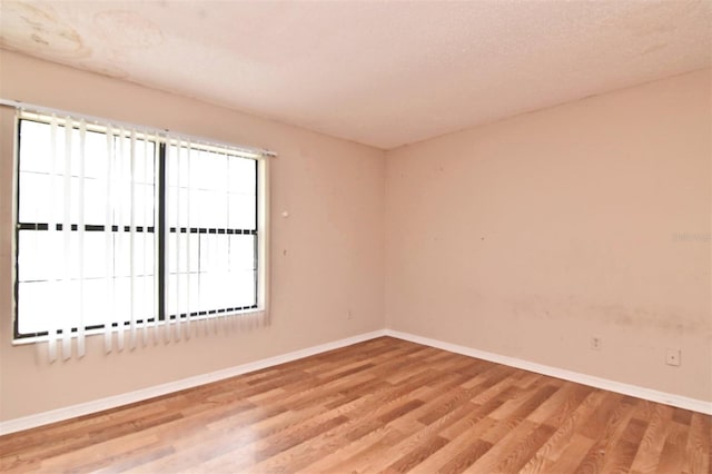 empty room featuring light wood-type flooring and a textured ceiling