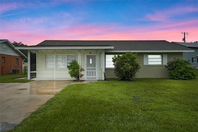 ranch-style home with a yard and central air condition unit