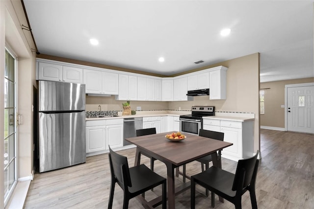 kitchen featuring appliances with stainless steel finishes, white cabinetry, sink, and light hardwood / wood-style floors