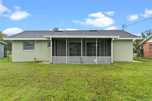 rear view of house featuring a sunroom and a yard