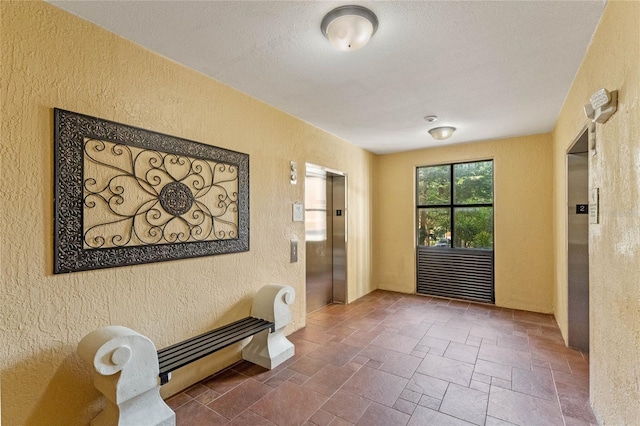 12556 Floridays Resort Dr Unit 207-A, Orlando, FL 32821 - hallway featuring elevator, stone finish floor, and a textured wall