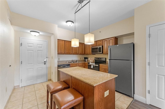 kitchen featuring pendant lighting, sink, appliances with stainless steel finishes, a center island, and a kitchen bar