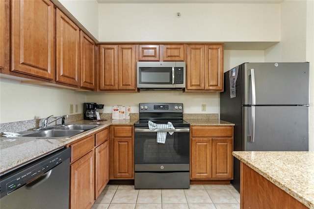 kitchen with stainless steel appliances, light stone counters, light tile patterned flooring, and sink