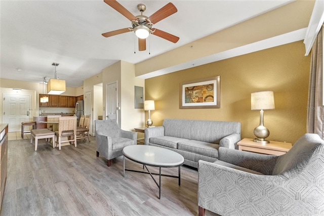 living room with light hardwood / wood-style flooring, ceiling fan, and electric panel