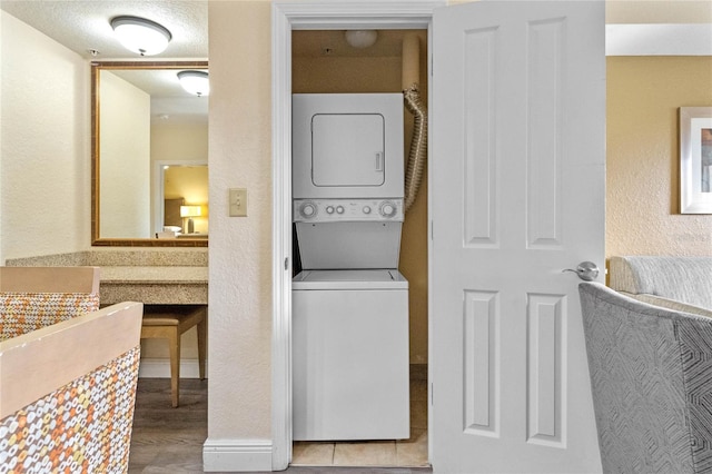 laundry area featuring stacked washer / dryer, a textured ceiling, and hardwood / wood-style floors