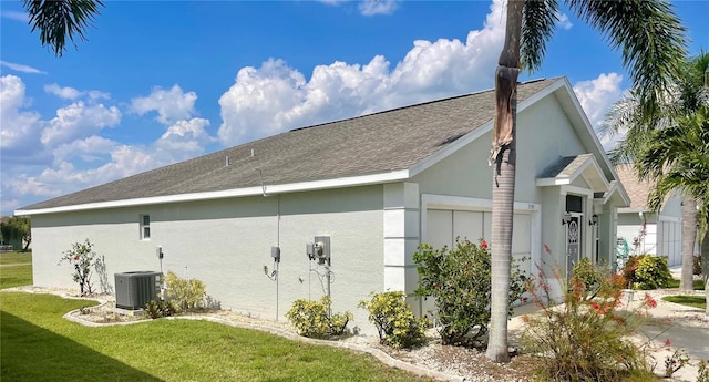 view of home's exterior featuring cooling unit, a garage, and a lawn