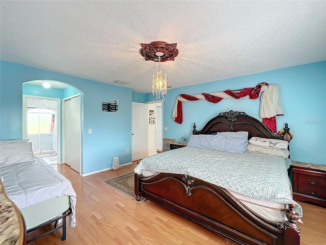 bedroom featuring a textured ceiling, a notable chandelier, and wood-type flooring