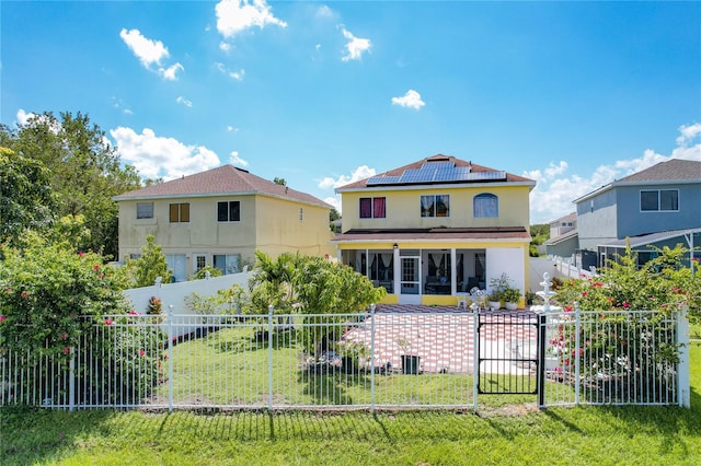 rear view of property featuring central AC unit, a yard, a sunroom, and solar panels