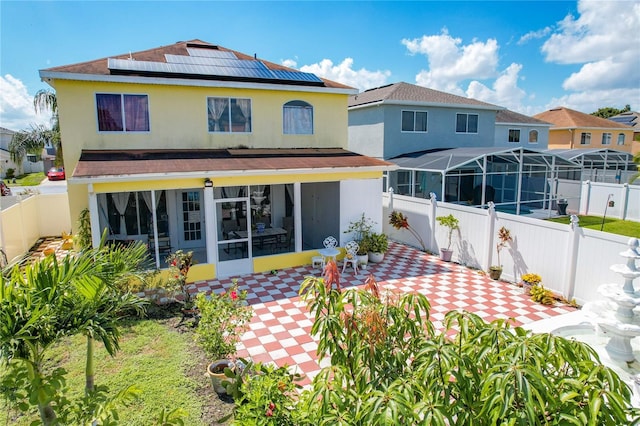 rear view of house featuring solar panels and a patio