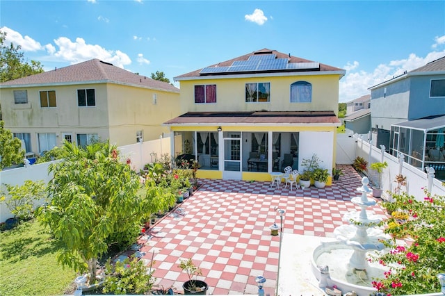 rear view of house with solar panels, a patio area, and a sunroom